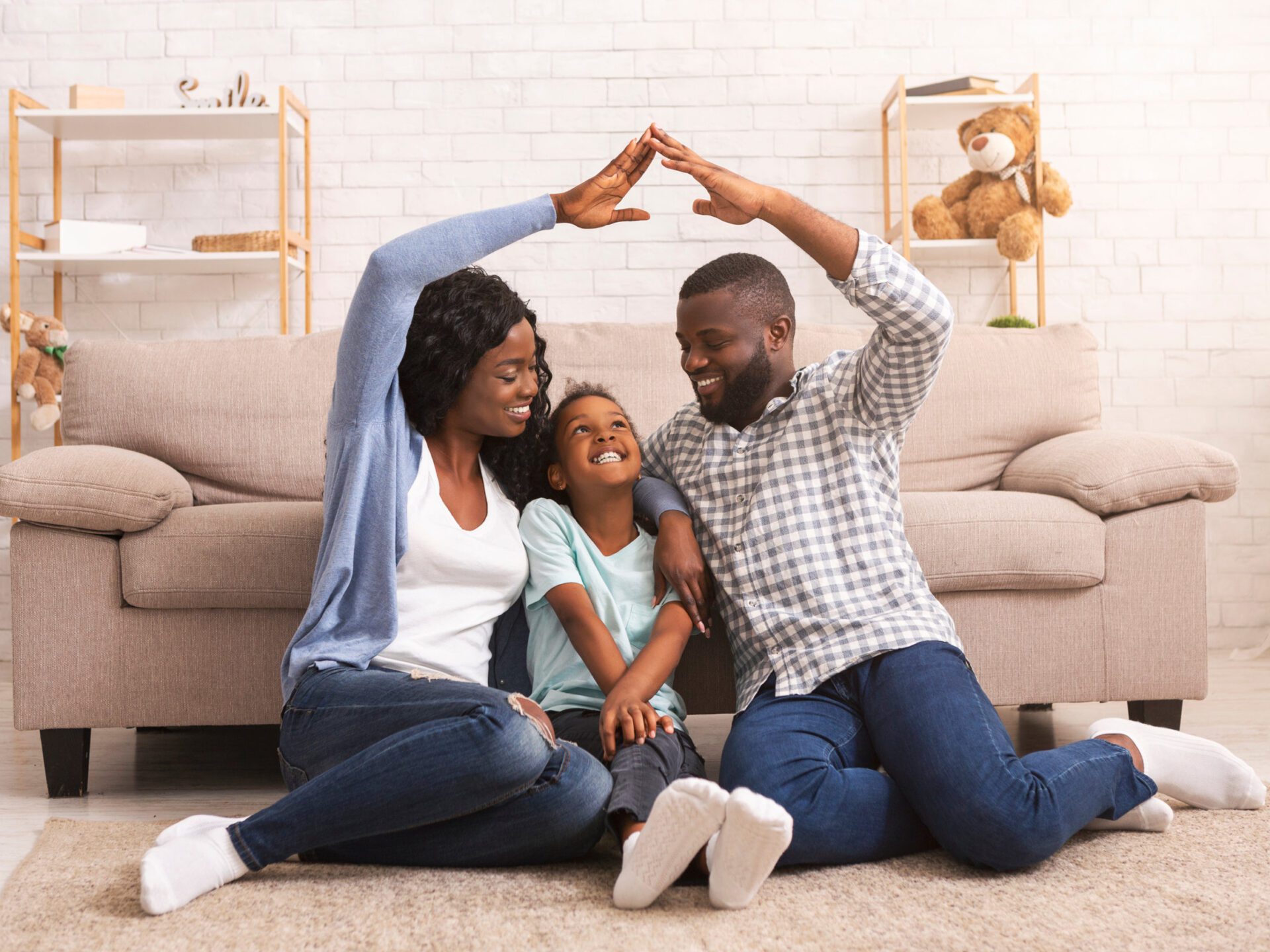 Parents making symbolic roof of hands above little daughter's head Home Insurance